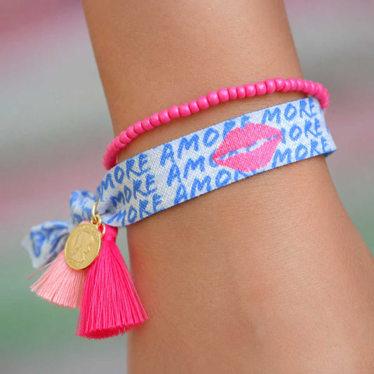Elastisches Armband-Set Amore Kiss mit Amore-Kuss-Band und pinkem Perlenarmband am Handgelenk getragen – pinke Quaste mit goldenem Anhänger, Saltyblush