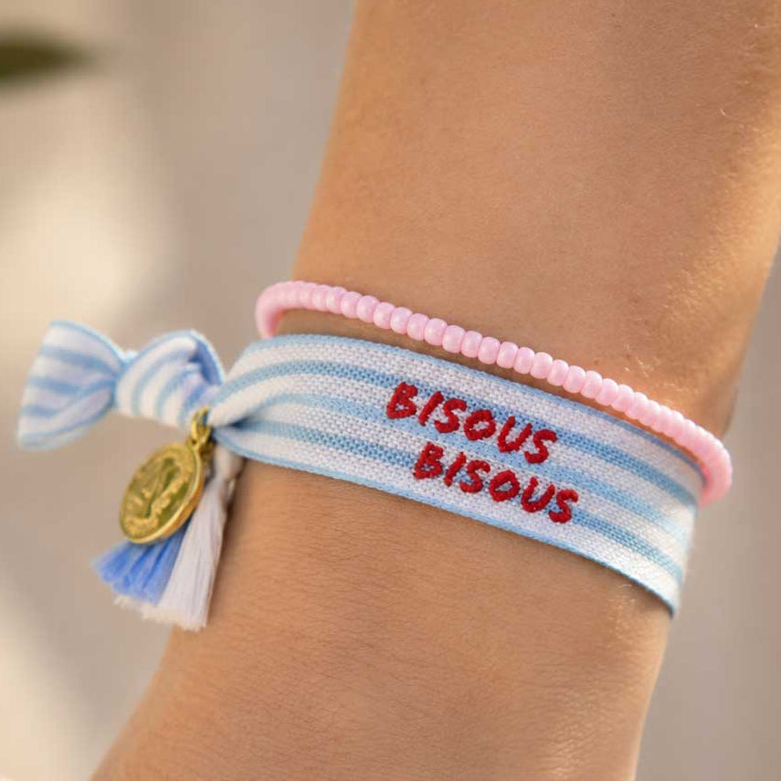 Elastisches Armband-Set Bisous Bisous – hellblaues Streifenband mit rotem Schriftzug und rosa Perlenarmband kombiniert am Handgelenk – goldener Münzanhänger, Saltyblush