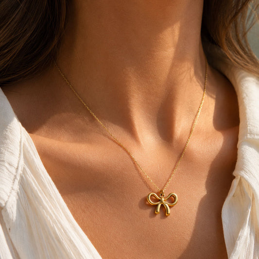 Goldene Halskette Bow Glow mit Schleifen-Anhänger am Hals getragen – Edelstahl, Saltyblush