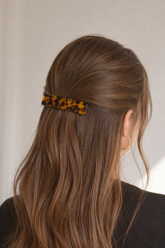 Frau mit langen braunen Haaren trägt die Amber Curve Haarspange im Schildpatt-Design als Halbhochsteckfrisur – Saltyblush