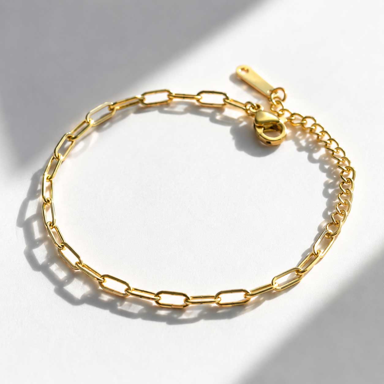 Goldenes Paperclip-Armband mit Karabinerverschluss und Verlängerungskette auf weißem Untergrund, vergoldetes Gliederarmband als Charm-Basis