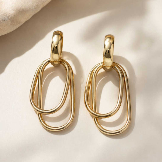 Goldene Ohrringe mit doppelten ovalen Ringen auf hellem Hintergrund – Golden Loop von Saltyblush