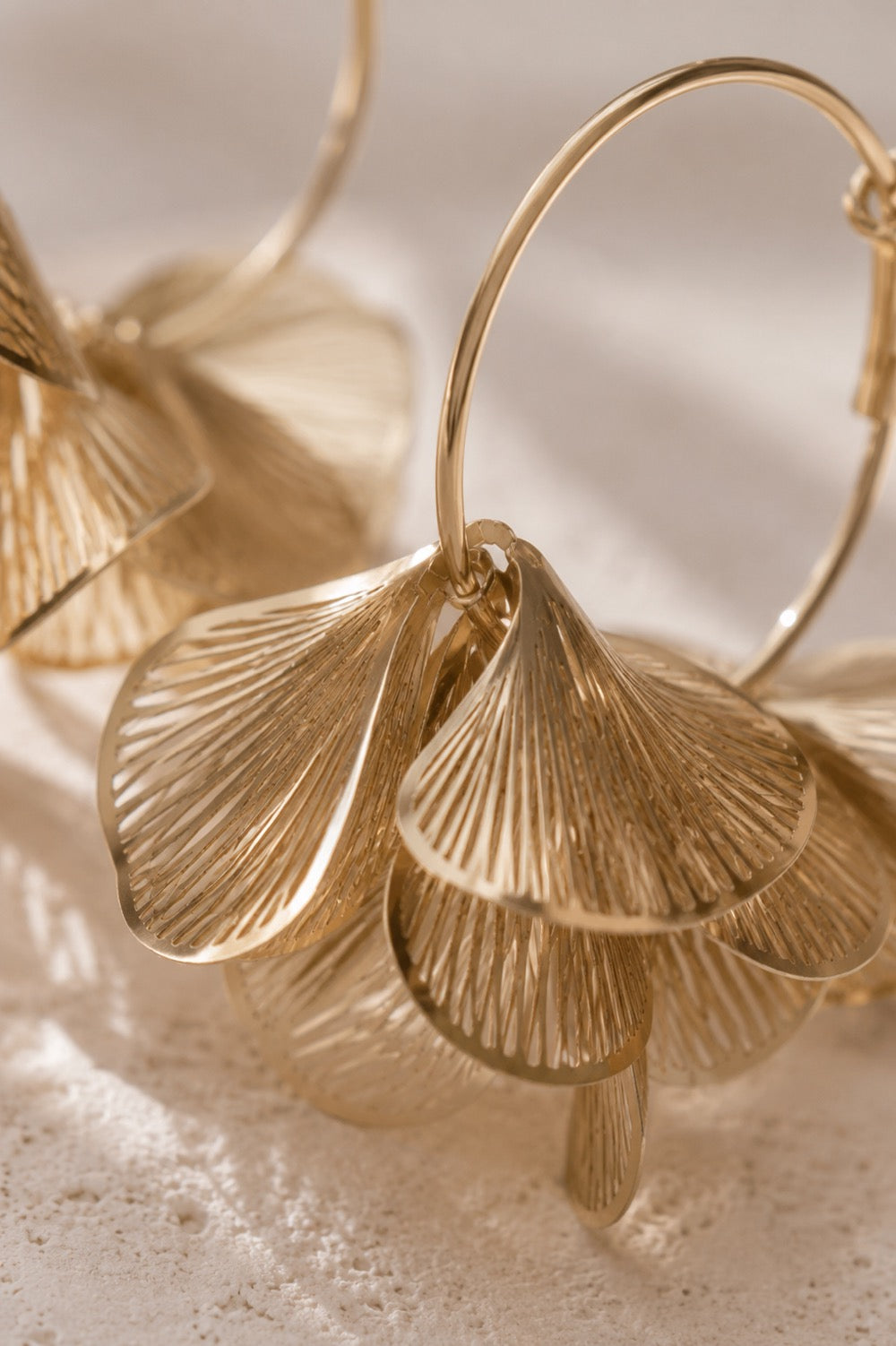 Detailaufnahme goldener Creolen mit strukturierten Blütenblatt-Anhängern im Sonnenlicht – Golden Petal Hoops von Saltyblush