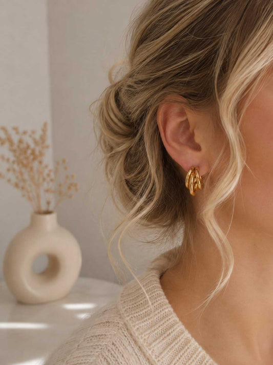 Golden Wave Hoops goldene Creolen am Ohr getragen mit hochgestecktem blondem Haar und beigem Pullover – Saltyblush