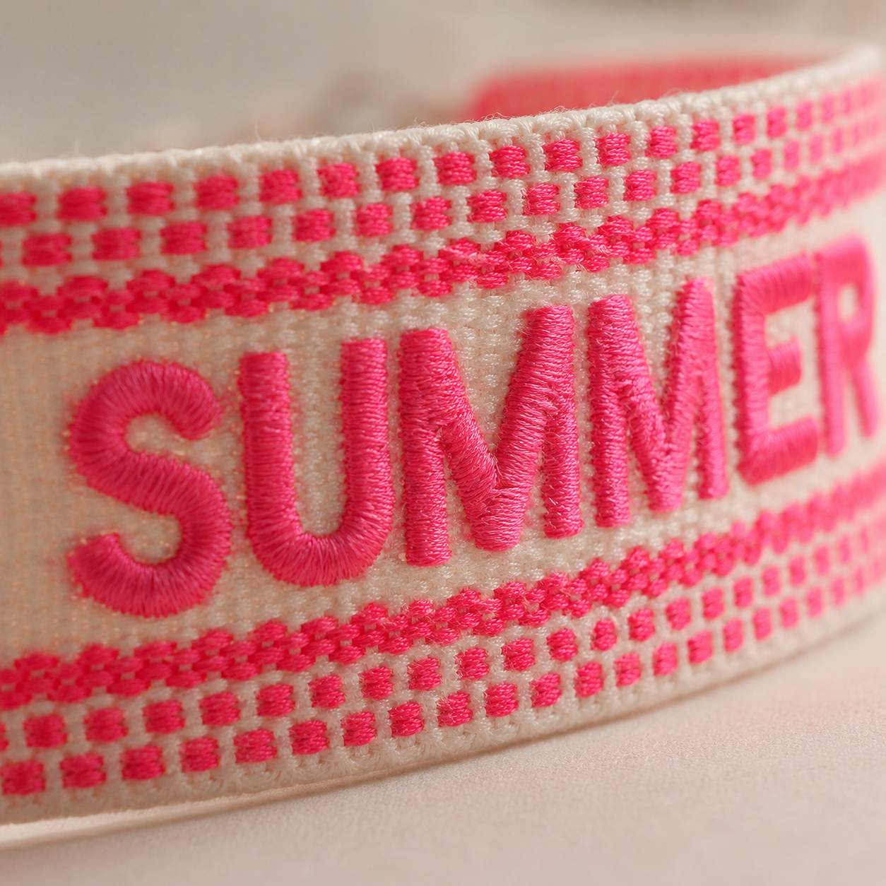 Detailansicht gestickter Schriftzug „Summer" auf gewebtem Armband in Pink und Creme – Saltyblush