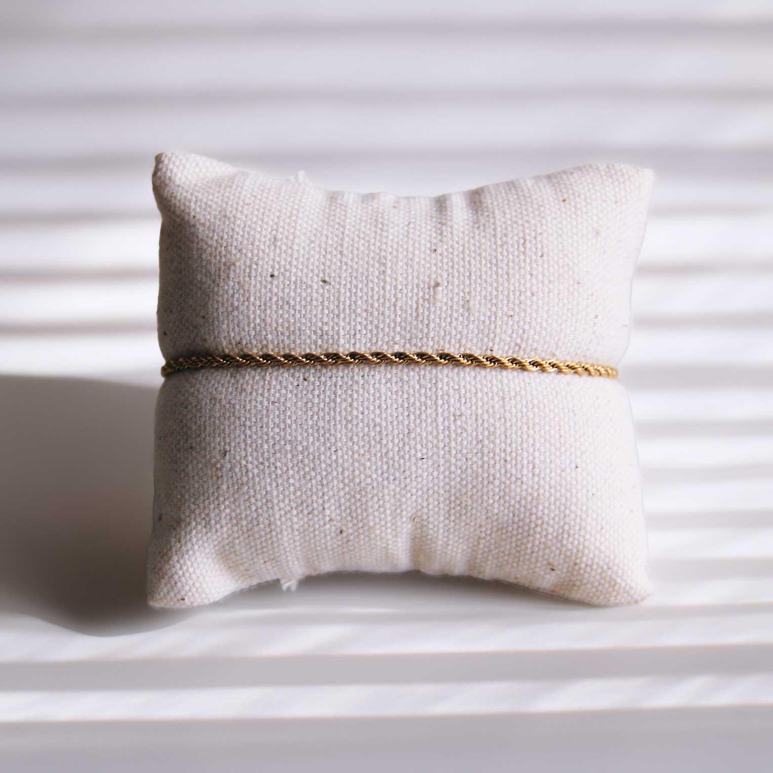 Goldenes Edelstahl-Armband Soft Twist auf weißem Schmuckkissen – Saltyblush
