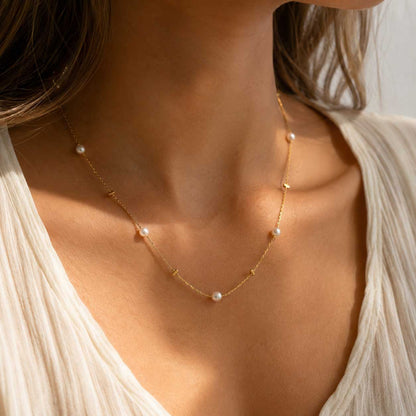 Golden Pearl Halskette getragen – goldene Perlenkette von Saltyblush am Hals einer Frau, zarte weiße Perlen auf feiner Goldkette, zu weißem Oberteil im Sonnenlicht
