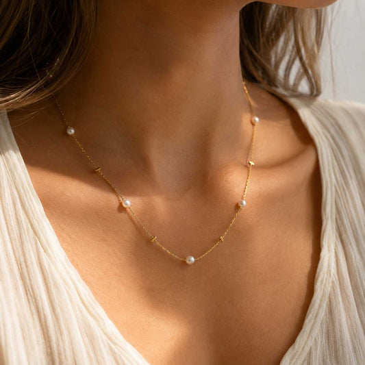 Golden Pearl Halskette getragen – goldene Perlenkette von Saltyblush am Hals einer Frau, zarte weiße Perlen auf feiner Goldkette, zu weißem Oberteil im Sonnenlicht
