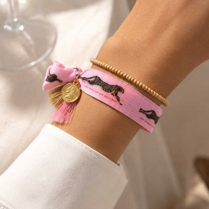 Elastisches Armband-Set Leopard in Rosa mit Leopard-Print-Band und beigem Holzperlenarmband am Handgelenk getragen – pinke Quaste mit goldenem Münzanhänger, Saltyblush

