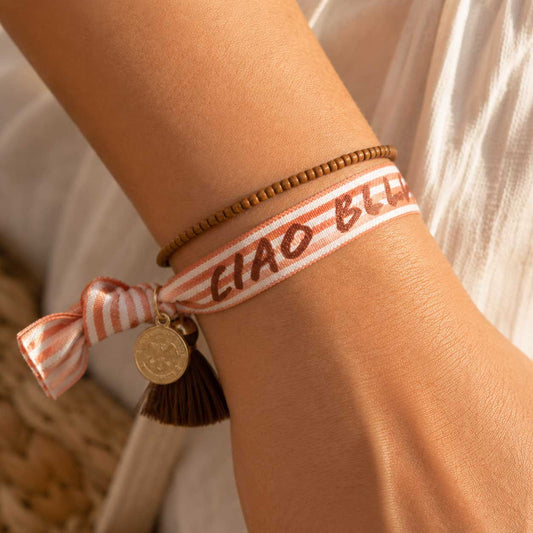 Elastisches Armband-Set Ciao Bella mit „Ciao Bella"-Streifenband und braunem Perlenarmband am Handgelenk getragen – Saltyblush
