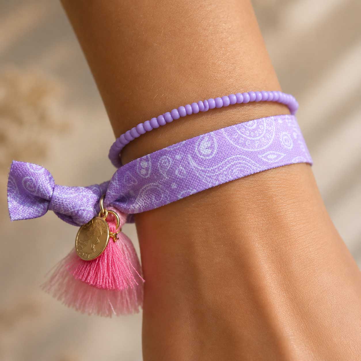 Elastisches Armband-Set Lavender Paisley mit Paisley-Band und Perlenarmband am Handgelenk getragen – pinke Quaste mit goldenem Anhänger, Saltyblush
