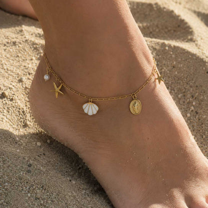 Goldene Fußkette Sea Whisper mit Meer-Charms am Fuß getragen am Strand – Saltyblush
