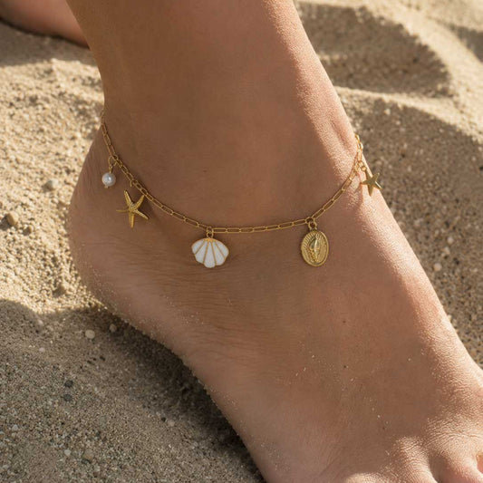 Goldene Fußkette Sea Whisper mit Meer-Charms am Fuß getragen am Strand – Saltyblush
