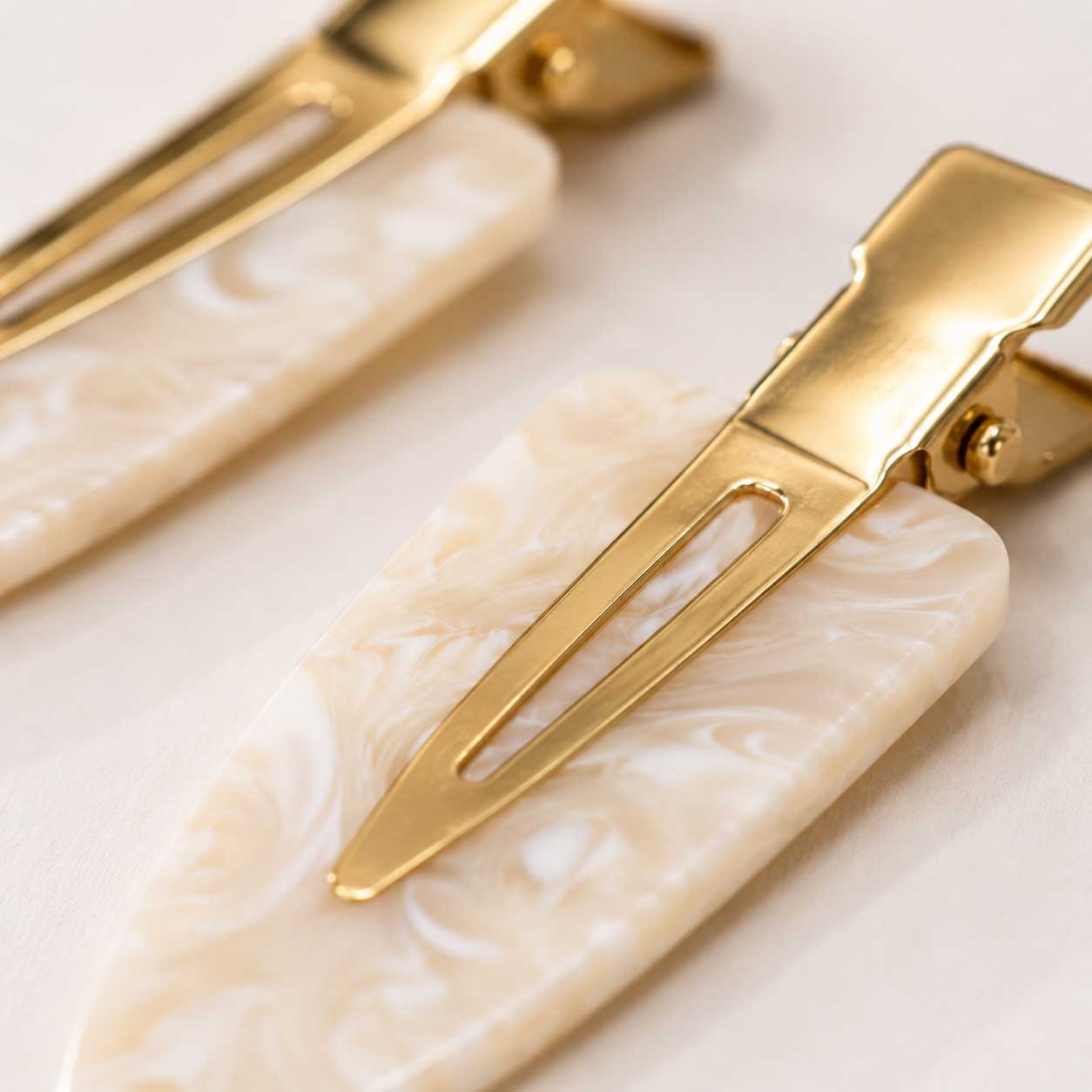 Nahaufnahme Ivory Pearl Haarclip – goldfarbener Klipp-Mechanismus und marmorierte Kunststoffoberfläche
