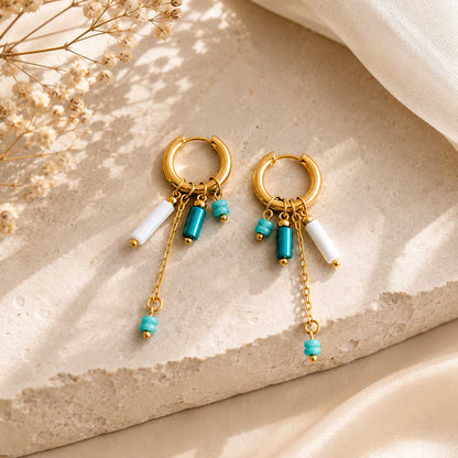 Goldene Creolen Blue Tide mit türkisen und weißen Perlen auf beigem Stein – Saltyblush
