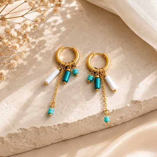Goldene Creolen Blue Tide mit türkisen und weißen Perlen auf beigem Stein – Saltyblush
