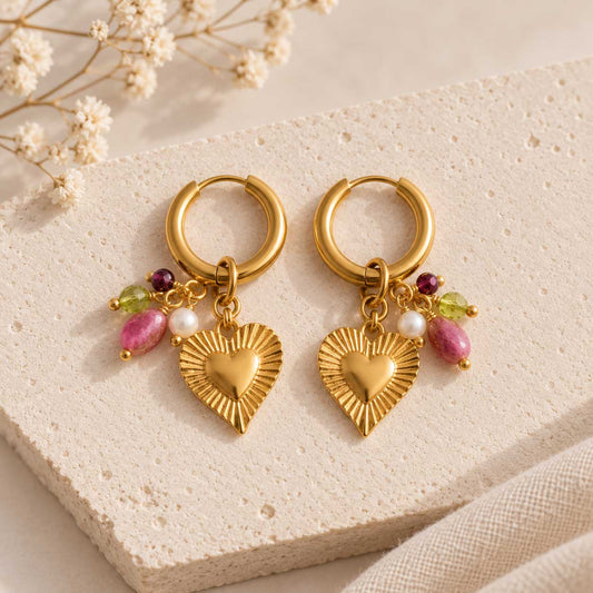 Goldene Creolen Dolce Cuore mit Herz-Charm und pinken Perlen auf beigem Stein – Saltyblush
