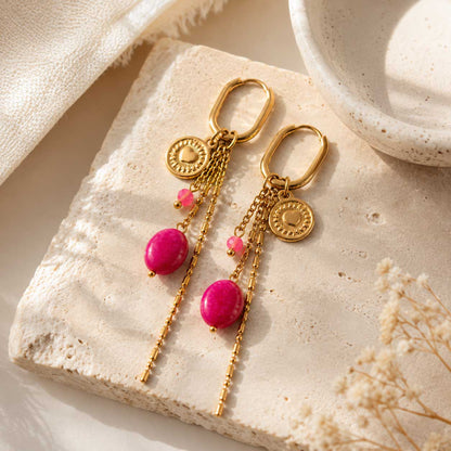 Goldene Ohrringe Golden Blush mit pinker Perle auf beigem Untergrund – Saltyblush
