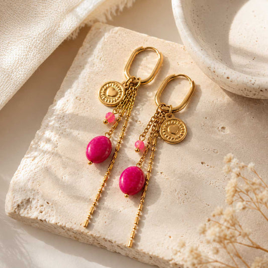 Goldene Ohrringe Golden Blush mit pinker Perle auf beigem Untergrund – Saltyblush
