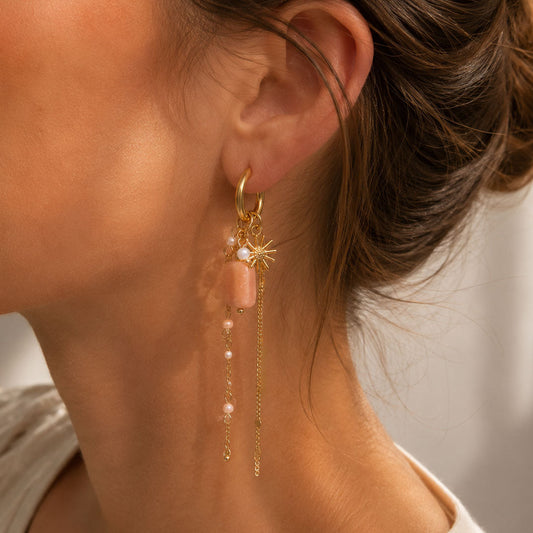 Goldene Statement-Ohrringe Rosé Ray mit Sonnenstern, rosafarbenem Stein und Goldketten am Ohr – Saltyblush
