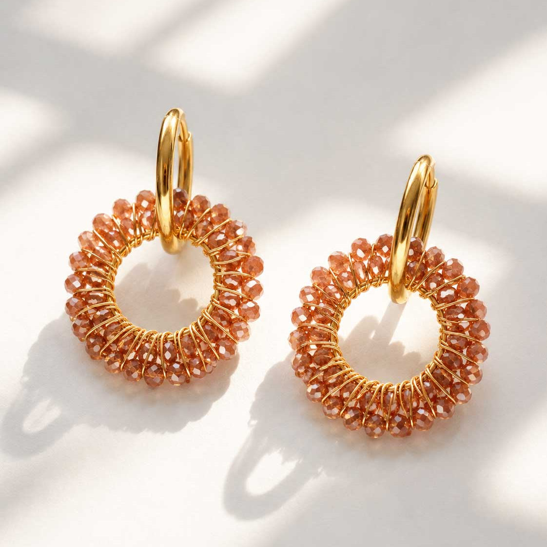 Goldene Creolen Mokka Glow Hoops mit terrakottafarbenen facettierten Glasperlen auf weißem Hintergrund – Edelstahl, Saltyblush
