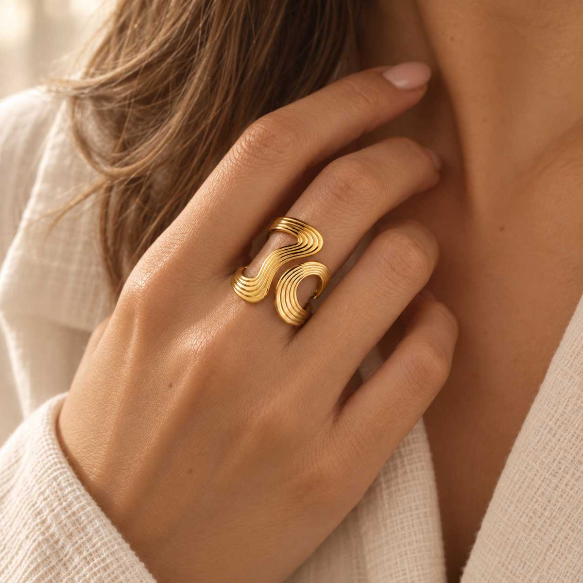 Detailaufnahme des goldfarbenen XL Swirl Rings aus Edelstahl mit auffälliger, geschwungener Streifenoptik und markanter Statement-Form
[AI]