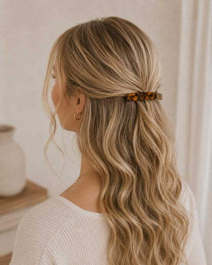 Frau mit langen blonden Wellen trägt die Amber Curve Haarspange im Schildpatt-Design als Halbhochsteckfrisur – Saltyblush
