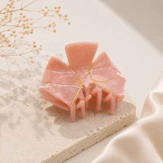 Aurabow Haarklammer in Rosa – Blütenform aus Kunststoff mit goldenen Kintsugi-Details, Produktfoto auf hellem Untergrund
