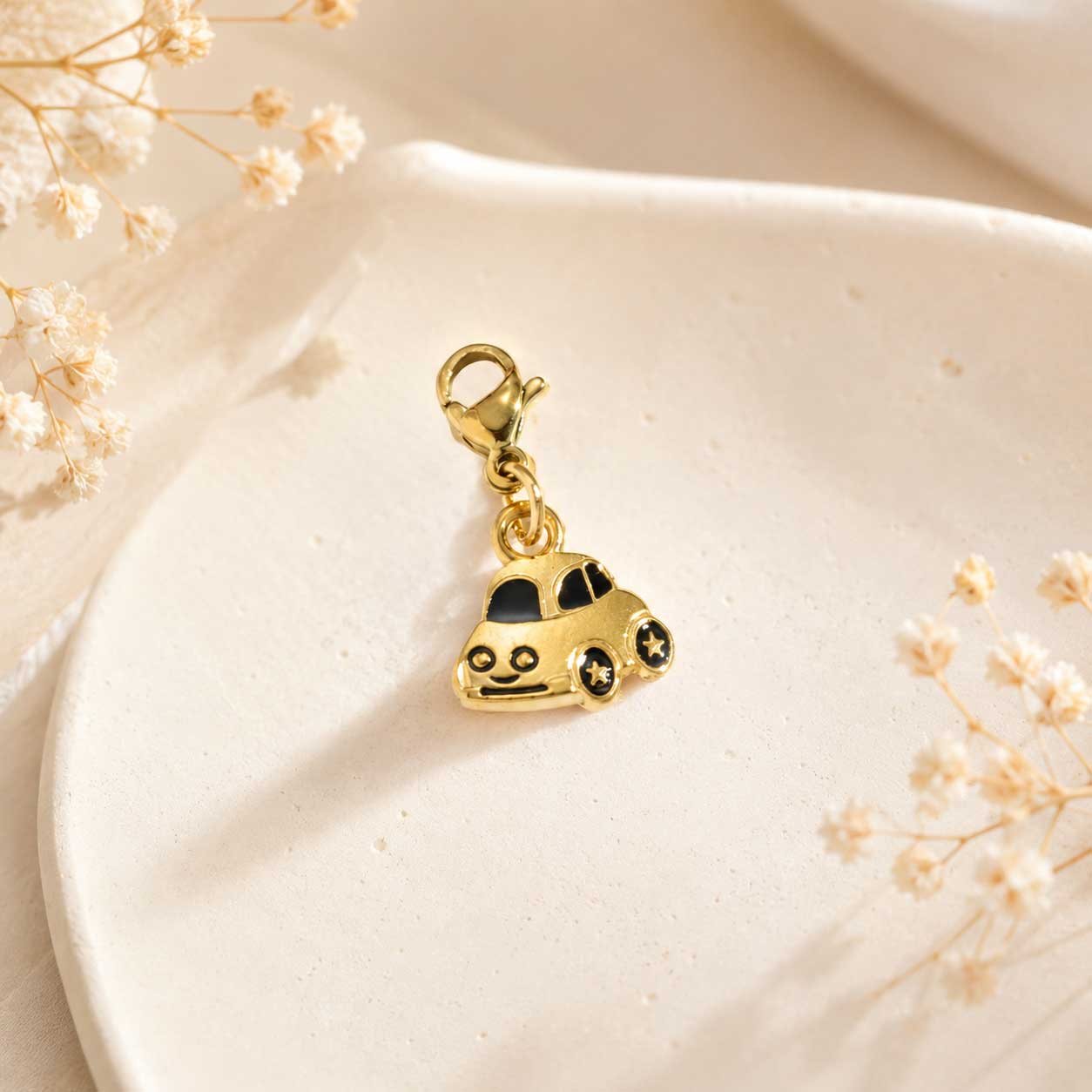 Goldener Auto-Charm mit schwarzen Akzenten und Karabinerverschluss auf weißem Tablett – Charm Concept Saltyblush
