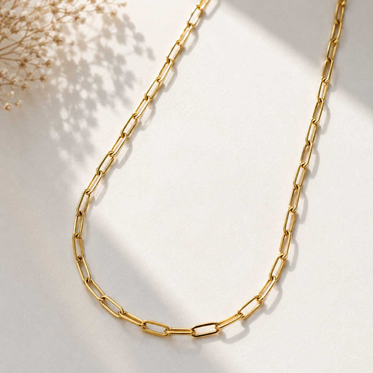 Goldene Paperclip-Halskette auf hellem Untergrund mit Schleierkraut, vergoldete Gliederkette aus Edelstahl mit länglichen Ösen
