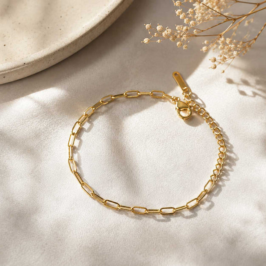Goldenes Paperclip-Armband auf hellem Stoff mit Schleierkraut, vergoldetes Gliederarmband mit Karabinerverschluss und Verlängerungskette
