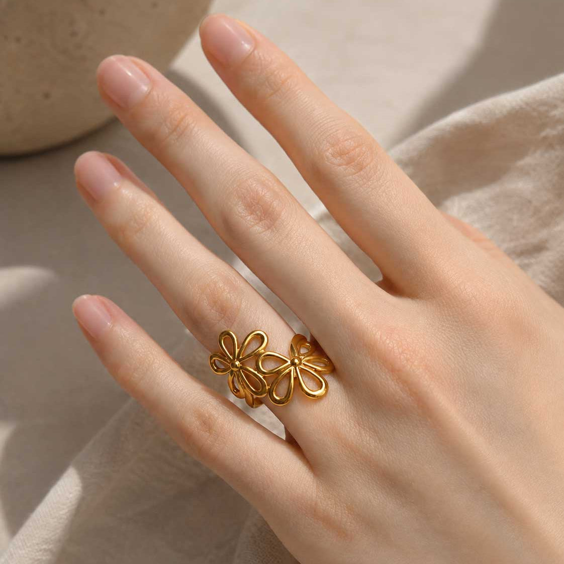 Blossom Glow Ring am Finger getragen – goldener verstellbarer Blütenring, Nahaufnahme Hand, Edelstahl, Saltyblush
[AI]