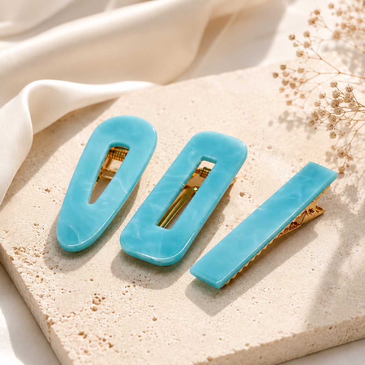 Türkisfarbenes Haarspangen-Set mit 3 Stück auf Sandstein, blaue Acryl-Haarclips in verschiedenen Formen mit goldenem Verschluss
