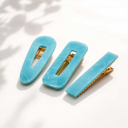 Türkisfarbenes Haarspangen-Set 3 Stück auf weißem Hintergrund, blaue Acryl-Haarclips in oval, rechteckig und eckig mit goldenem Clip

