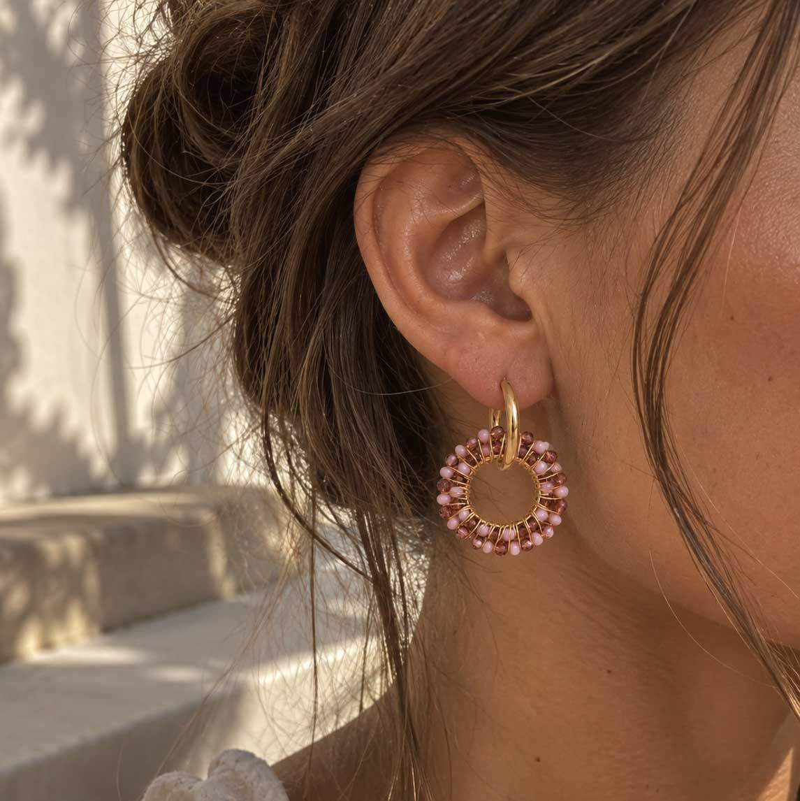 Blush Beaded Hoops goldene Creolen mit rosa Perlenring am Ohr getragen, Sonnen-Lifestyle-Shot
[AI]
