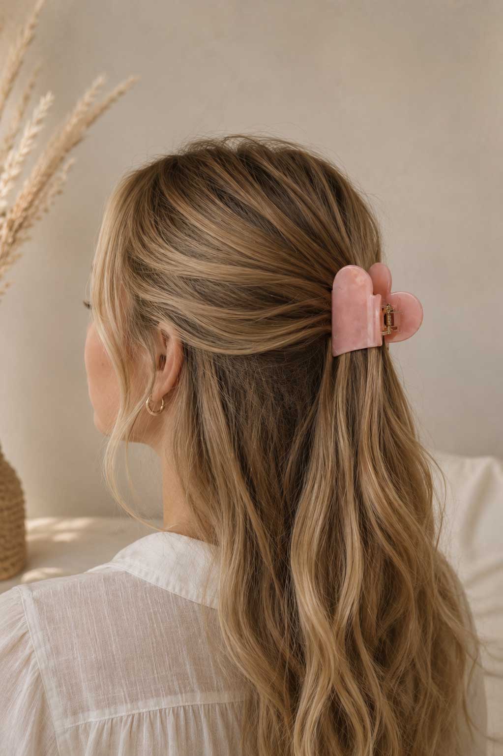 Blonde Frau mit langen Wellen trägt rosa herzförmige Haarklammer im Half-Up-Style – Lifestyle-Aufnahme – Saltyblush
