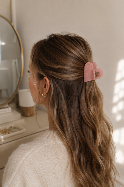 Frau mit langen braunen Haaren trägt rosa herzförmige Haarklammer im Half-Up-Style – Lifestyle-Aufnahme – Saltyblush
