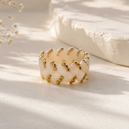 Cremefarbener Miyuki-Perlenring mit goldenen Rocailles in Flechtmuster, handgefertigter Beaded Ring in Creme-Gold auf grauem Untergrund
