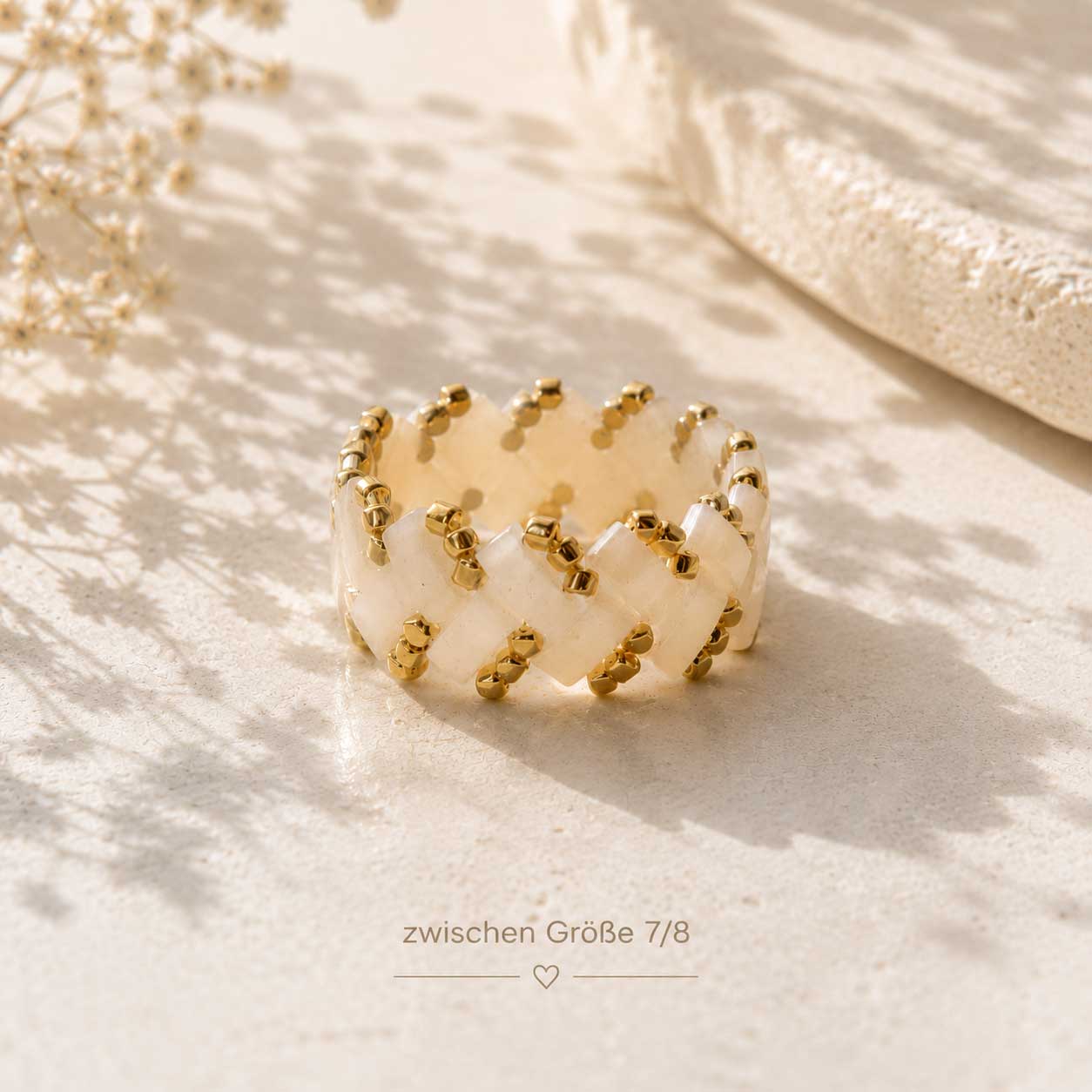Rosa Miyuki-Perlenring am Mittelfinger getragen, handgefertigter Beaded Ring in Rosa-Gold zu weißem Spitzenoberteil und Jeans
