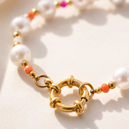 Nahaufnahme des goldenen Ringverschlusses am Candy Pearl Armband, Detailansicht des vergoldeten Edelstahl-Karabinerringes mit weißen Perlen und orangefarbenen Kristallen
