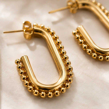 Detailaufnahme celeste glow Ohrringe – goldener Kugelrand und glänzende Oberfläche aus Edelstahl
