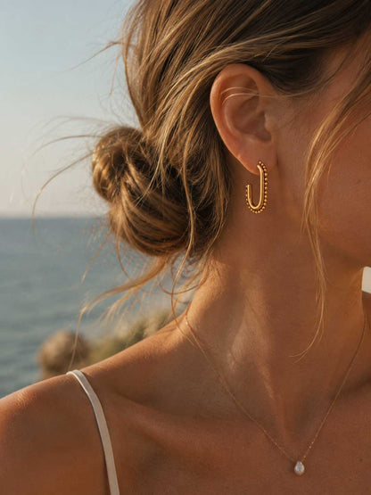 Frau trägt celeste glow goldene Creolen am Strand – Lifestyle-Aufnahme im Sonnenlicht
