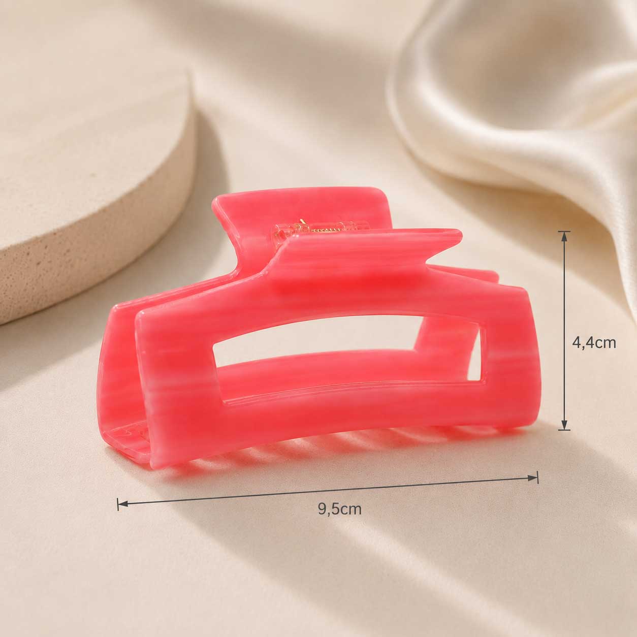 Coral Pop Haarklammer aus Acryl in Korallrot mit Maßangaben 9,5 cm x 4,4 cm auf cremefarbenem Seidenstoff – Saltyblush
