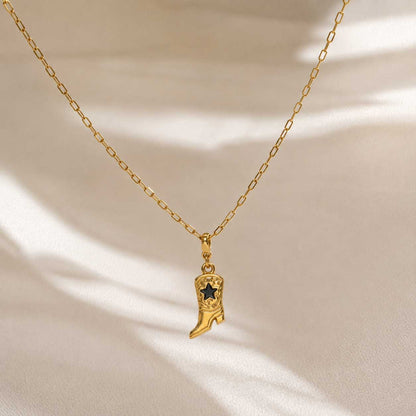 Goldene Gliederkette mit Cowboy Boot Charm in Gold-Schwarz auf cremefarbenem Hintergrund mit Lichtreflexen – Saltyblush
