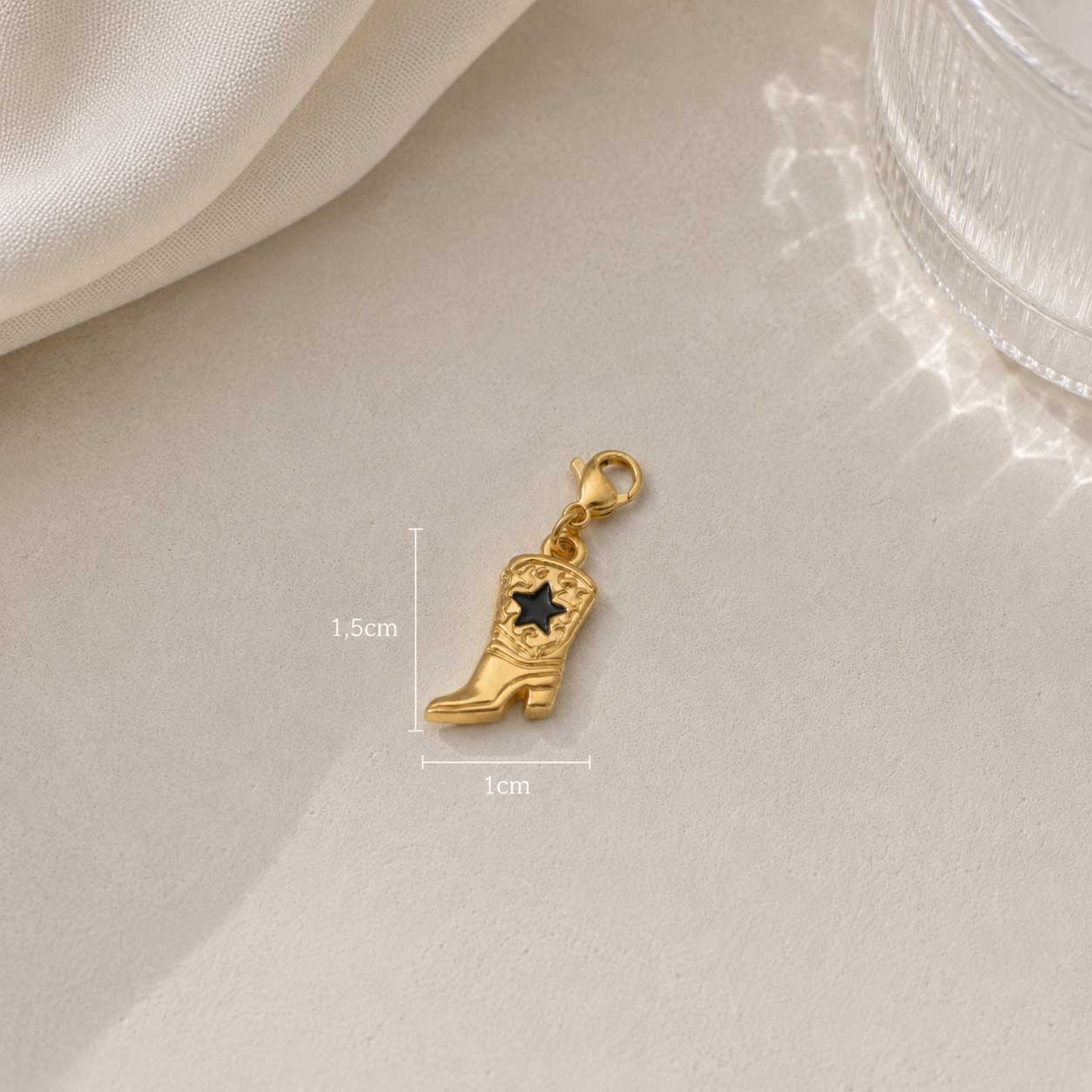 Cowboy Boot Charm aus Edelstahl in Gold mit Maßangaben 1,5 cm x 1 cm auf weißem Seidenstoff – Saltyblush
