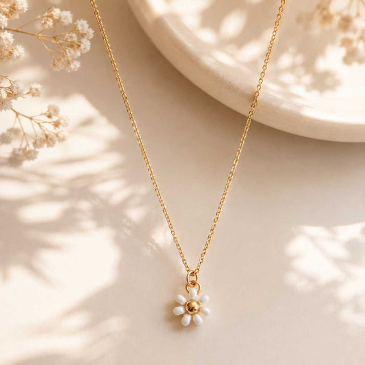 Goldene Halskette Daisy Bloom mit weißem Gänseblümchen-Anhänger auf cremefarbenem Hintergrund – Edelstahl, Saltyblush
