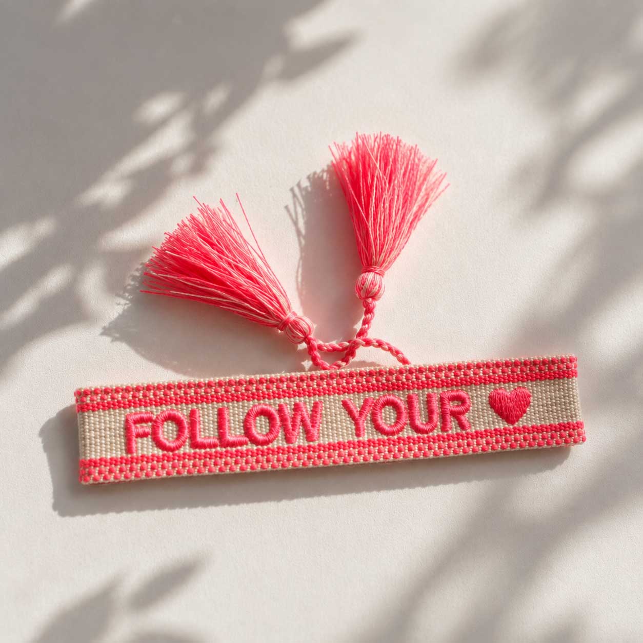 Follow Your Heart Armband aufgeklappt mit zwei pinken Quasten – Flatlay Produktfoto, Saltyblush Modeschmuck
