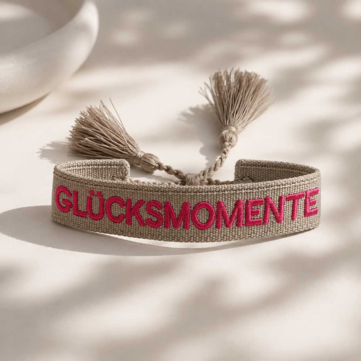 Glücksmomente Statement Armband in Grau mit pinkem Schriftzug und Quasten – gewebtes Arm
