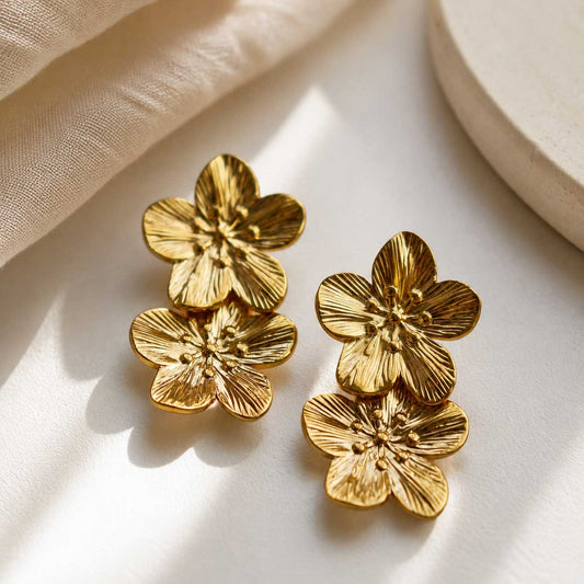 Golden Blossom Ohrringe aus Edelstahl mit doppeltem Blütendesign in Gold auf cremefarbenem Seidenstoff – Saltyblush
