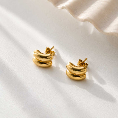 Goldene Curve Ohrringe aus Edelstahl mit doppelter Welle auf weißem Stoff – Saltyblush
